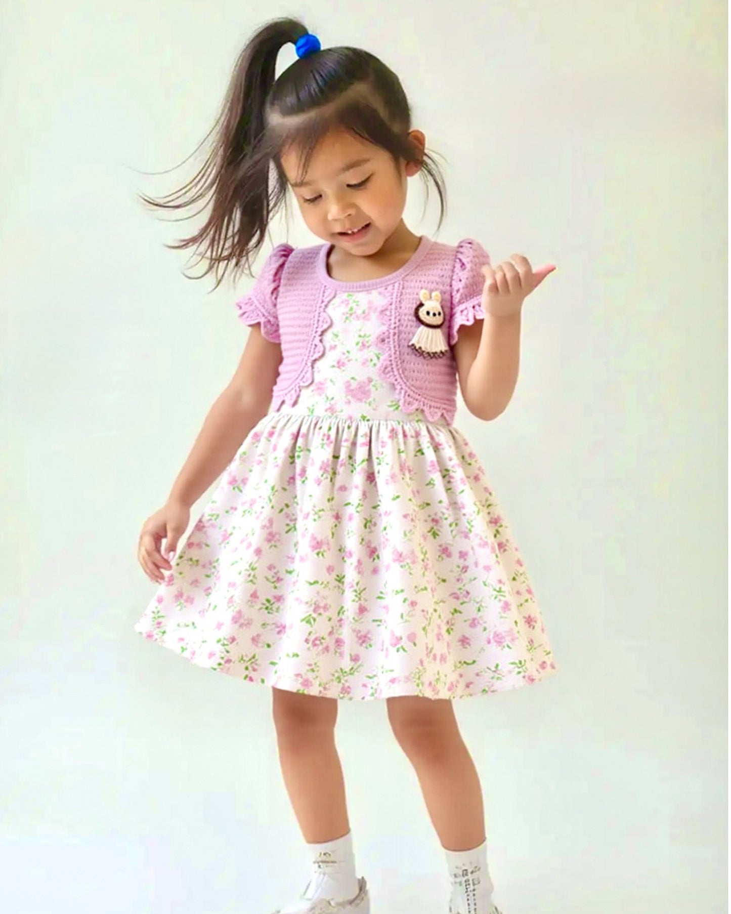 Young girl wearing a pink floral dress with a white background